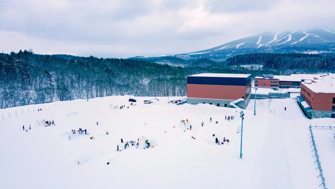 Igloo building on the campus field with Appi Kogen behind