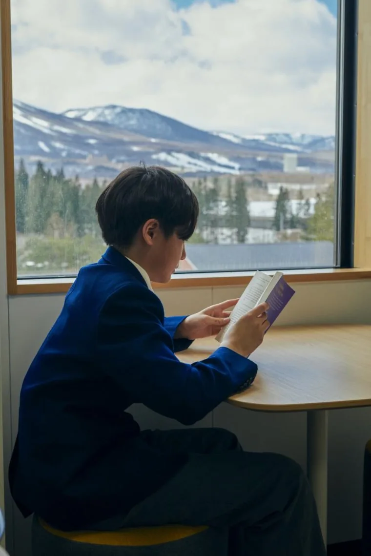 Student reading by the window with a mountain view