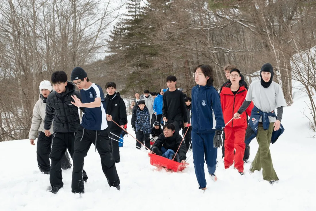 Students hauling a sledge through the snow at Appi Kogen